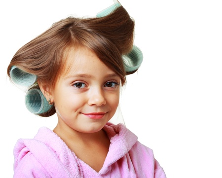cute five years old Girl with a comb in hair curlers on a white backgroundの写真素材