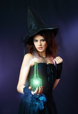 beautiful young sexy witch holding green bottle with portion. cosplay costume and make upの写真素材