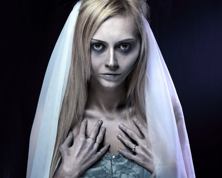Portrait of beautiful zombie corpse bride looked scary and standing at dark background. shot in...