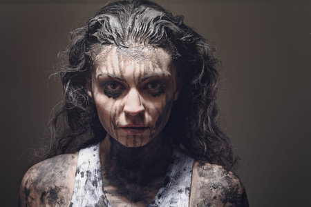a close up of a woman's face and hands covered in mud