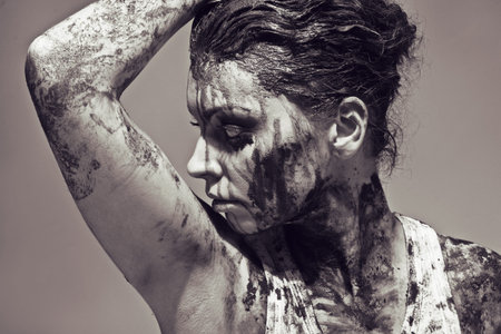 a close up of a woman's face and hands covered in mud