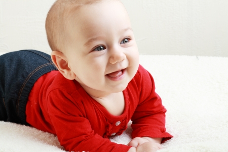 Close-up of sweet little baby laying on the white blanket smilingの写真素材