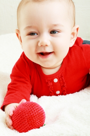 baby play with toy in red cloth smilingの写真素材