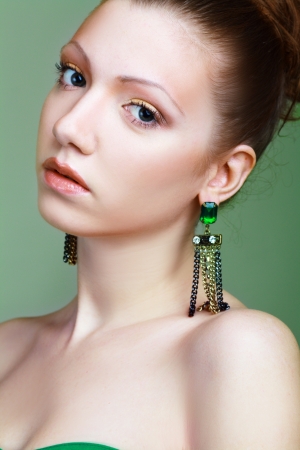 Portrait of beautiful woman with beautiful make-up and hairstyle. Elegant woman with green jewelry の写真素材