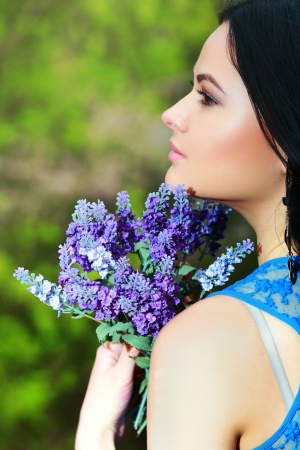 brunette woman with blue flowers in the park in springの写真素材