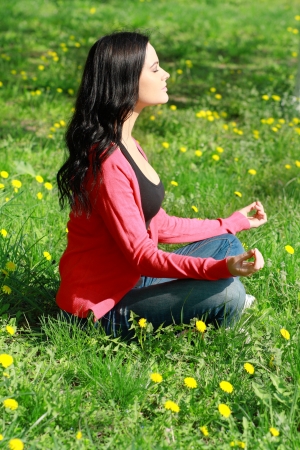 Beautiful Girl Doing Yoga Exercises in the park on green grassの写真素材