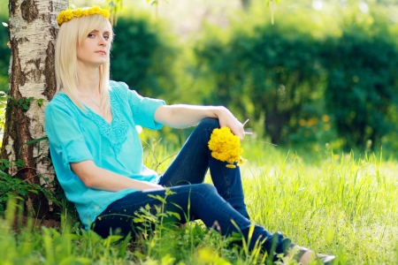 blond young woman relaxing in the grass in the city parkの写真素材
