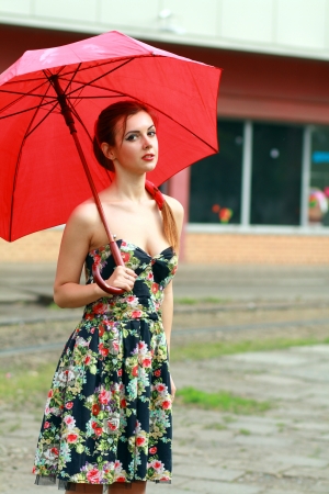 beautiful woman holding a red umbrella in the city streetの写真素材