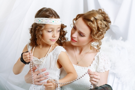 Smiling mother and baby daughter playing with jewelryの写真素材