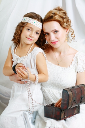 Smiling mother and baby daughter playing with jewelryの写真素材
