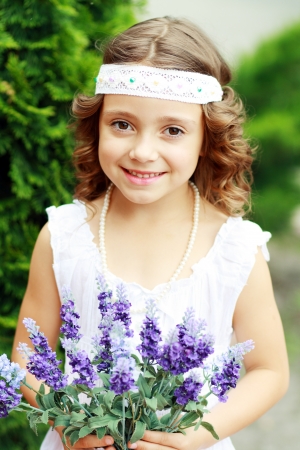 adorable little girl have fun with flowers in spring parkの写真素材