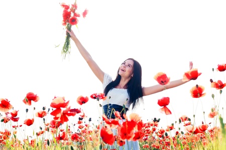 beauty woman in poppy field in white dress in a sunny summer dayの写真素材