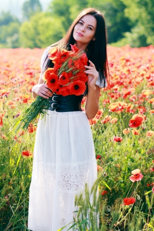 beauty woman in poppy field in white dressの写真素材