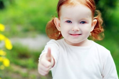 Little happy girl outdoor showing ok thumb upの写真素材