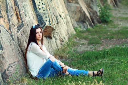 the beautiful young model sits on stonesの写真素材