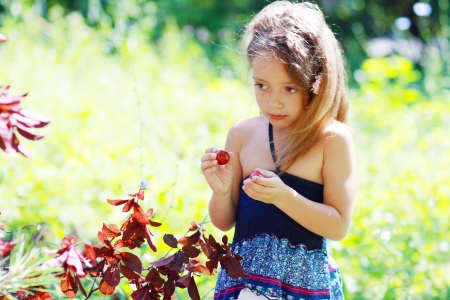 A little girl eating plum outdoor in sunny summer dayの写真素材