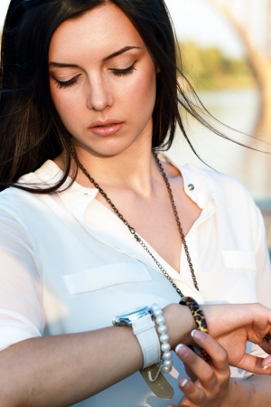 beautiful cheerful girl looks at watch on her hand, waiting for sombody. Date conceptの写真素材