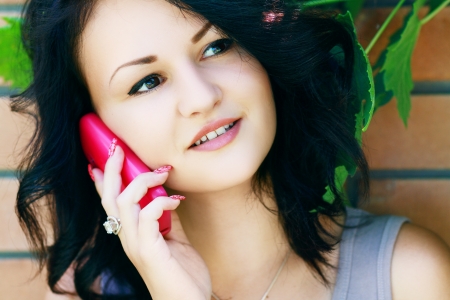 face of beautiful young woman talking at the cell phone at summerの写真素材