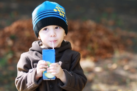 European two years old boy drinks juice and dreaming at the park の写真素材