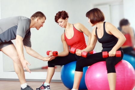 couch man explain how to do examples for two young woman in gymの写真素材