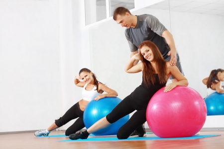 couch man explain how to do examples for two young woman in gymの写真素材