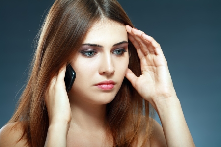 A young beautfiul woman is feeling sad as she is talking on here mobile cell phone. A young woman being sad. の写真素材