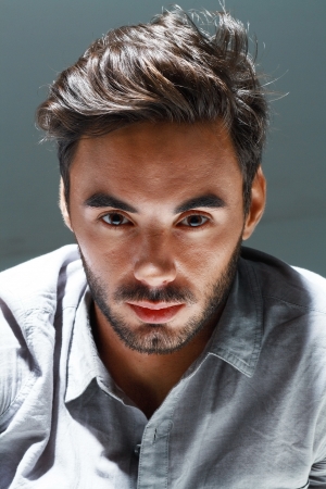 Portrait of young man studio shot with very handsome face in grey casual shirt against dark background の写真素材