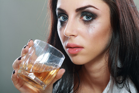 beautiful young crying woman in depression, crying and drinks alcohol Face close upの写真素材
