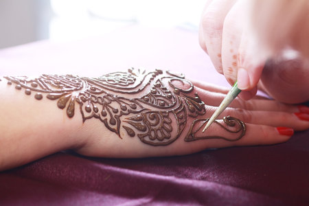 Image detail of henna being applied to hand close up