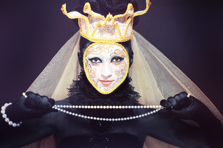 Beautiful woman with Venetian mask make up white and gold color with gold border and crownの写真素材