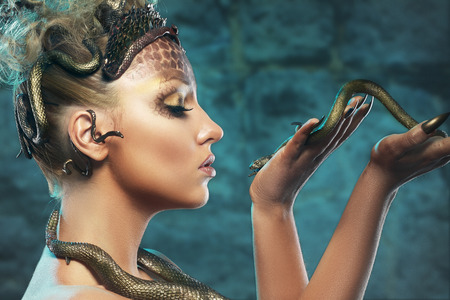 Gorgon medusa. Young woman with creative fantasy hairstyle and make up , holding a snake. の写真素材