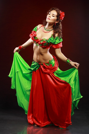 professional dancer beautiful woman dancing in green and red costume on blackの写真素材