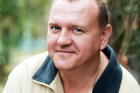 Head of friendly, handsome middle-aged man looking sidewards into camera.