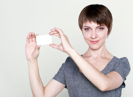 smiling business woman showing blank credit card isolated on white backgroundの写真素材