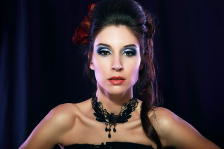 beautiful fashion vampire victorian style woman posing over dark backgroundの写真素材