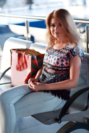 woman sitting on bench looking for the train inside railway station or waiting for the flight in airportの写真素材