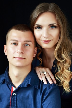 Portrait of a beautiful young couple in love posing at studio over dark background.の写真素材