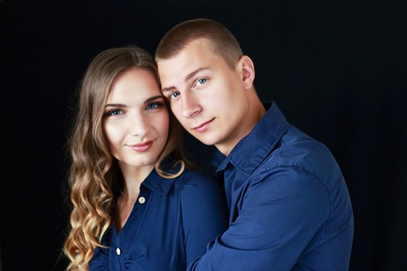 Portrait of a beautiful young couple in love posing at studio over dark background.の写真素材