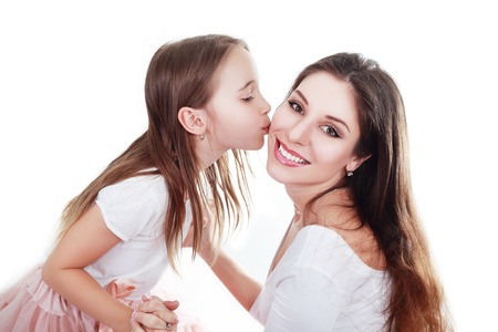 mother and daughter in same outfits posing on studio kissingの写真素材