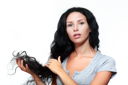 fashion portrait of a young woman holding her long straight curly volum hairの写真素材
