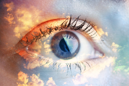 Double exposure portrait of macro eye combined with photograph of sky and clouds. Be creative!の写真素材
