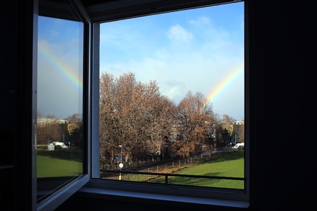 open window with rainbow outside city landscapeの写真素材