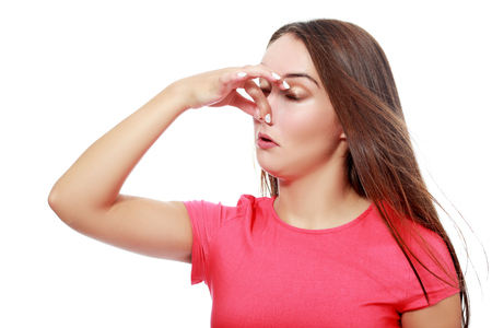 Closeup portrait of a young woman who covers her nose, looks away, something stinks, very bad smell, situation, isolated on white backgroundの写真素材