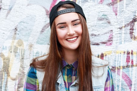 A teen girl wearing a cap on the street.の写真素材