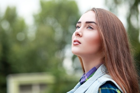 Gorgeous young spring brunette girl in nature, looking up at the sky.の写真素材