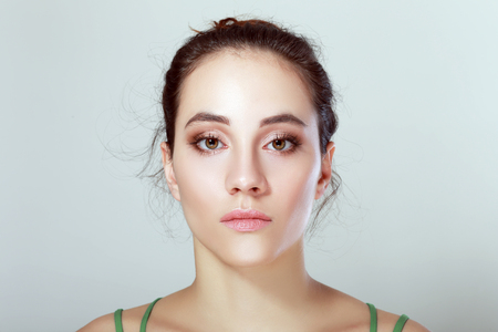 Front portrait of the woman with beauty face glowing skin - over grey backgroundの写真素材
