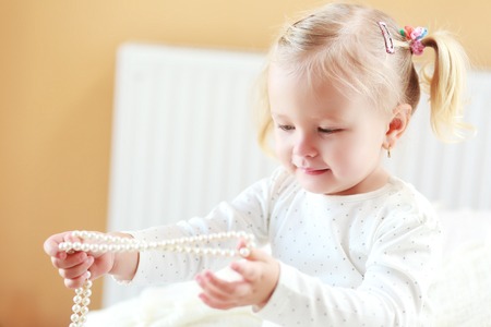 beautiful little girl plays with mother's jewelry close upの写真素材