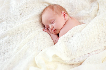 Newborn sleeping baby girl on a white blanketの写真素材