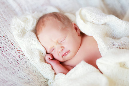 Newborn sleeping baby girl on a white blanket