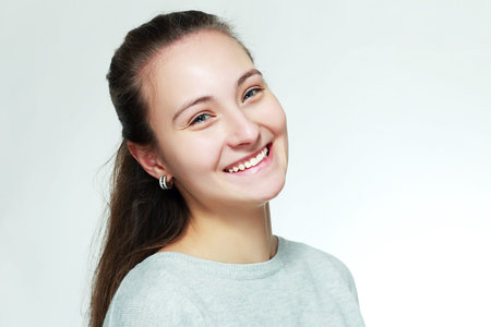 smiling young woman close-up face portrait without make-up with messy hair isolated on white...